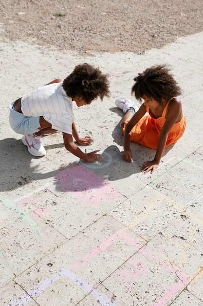 Niños dibujando en ángulo alto de pavimento