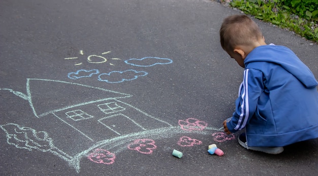 Niños dibujando en casa familiar de asfalto. Enfoque selectivo