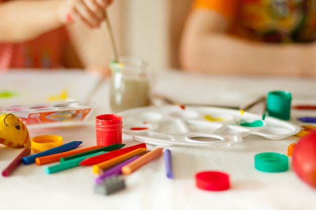 Niños dibujando con pinturas de colores en los papeles.