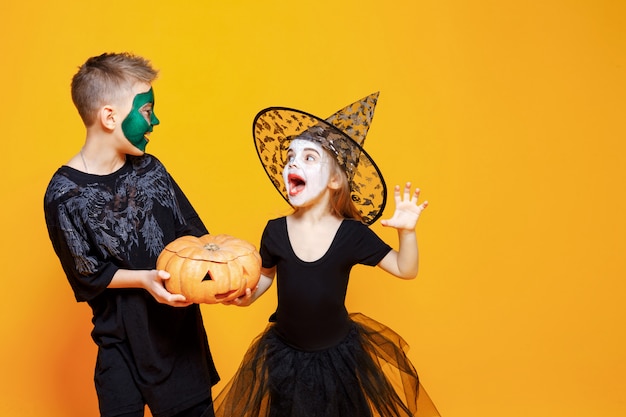 Foto niños en disfraces de halloween jugando con calabaza