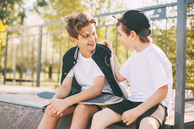 Foto los niños disfrutan de su tiempo libre en el skate park, sentados en la rampa. el concepto de juventud