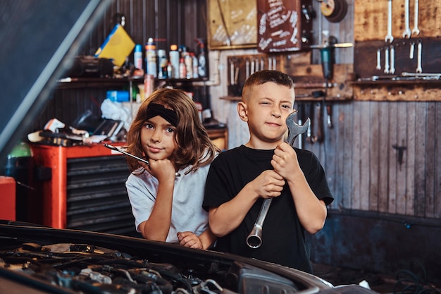 Los niños divertidos y alegres están tratando de arreglar un auto roto en un servicio de autos ocupado.