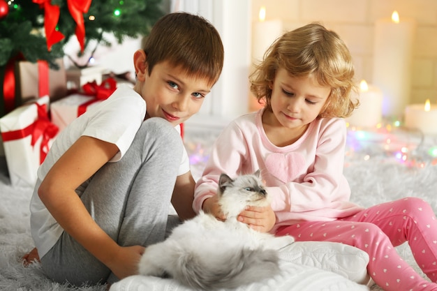 Niños divertidos con cajas de regalo y árbol de Navidad