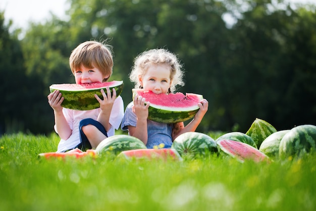 Niños divertidos comiendo sandía al aire libre.