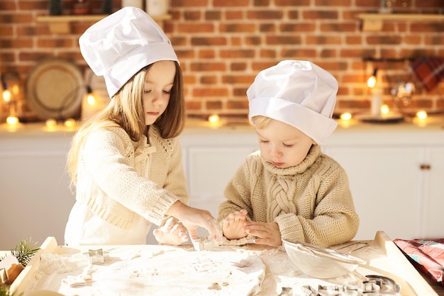 Los niños divertidos de la familia feliz están preparando la masa, jugando con la harina en la cocina.