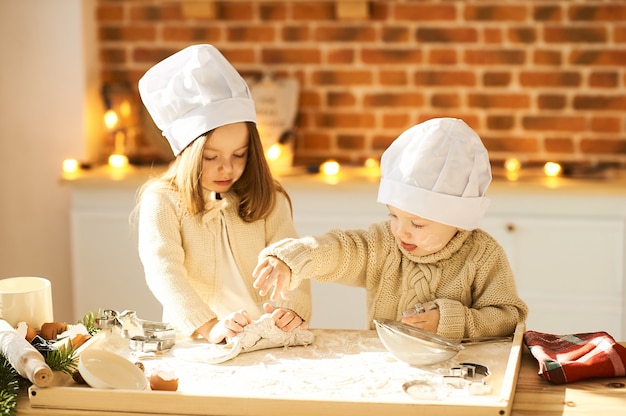 Los niños divertidos de la familia feliz están preparando la masa