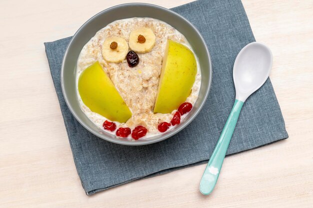 Niños divertidos niños bebés desayuno almuerzo gachas de avena en un tazón parecen búho con plátano de manzana