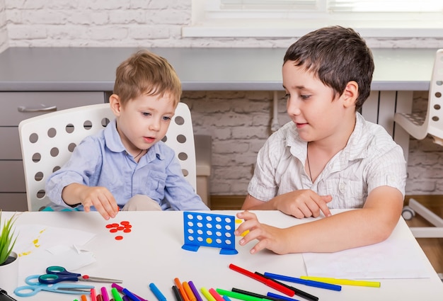 Niños divertidos sentados en la silla y jugando juntos al juego de mesa en casa