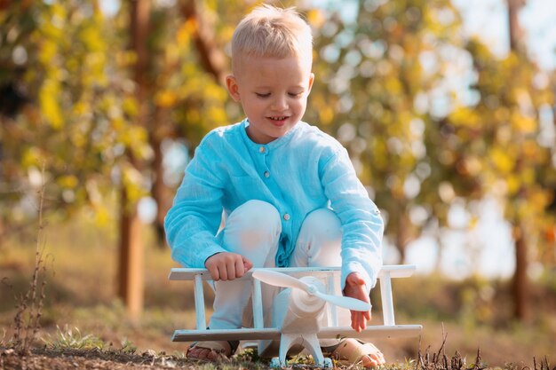 Los niños se divierten con un avión de juguete en el campo contra la naturaleza, la aventura y las vacaciones de fondo para niños