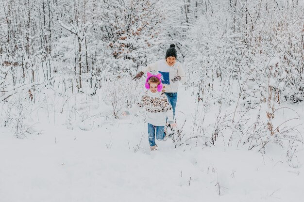 Los niños se divierten jugando en la nieve. niño y niña corriendo en Winter Park. vacaciones de invierno