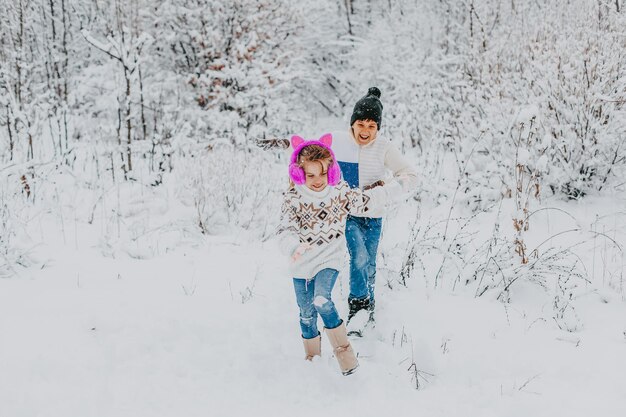 Los niños se divierten jugando en la nieve. niño y niña corriendo en Winter Park. vacaciones de invierno