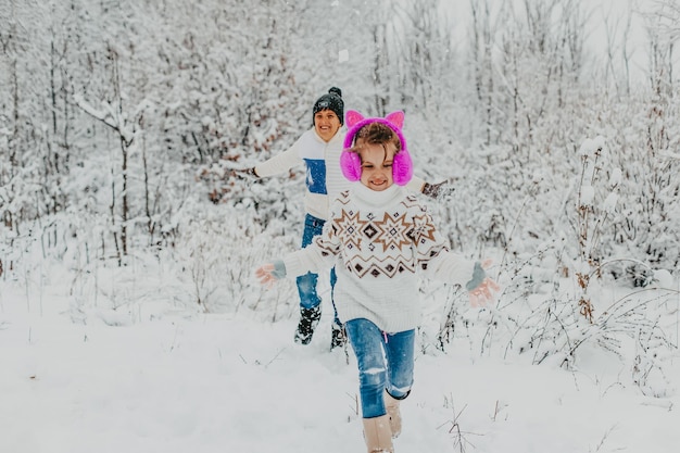 Los niños se divierten jugando en la nieve. niño y niña corriendo en Winter Park. vacaciones de invierno