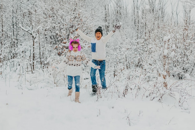 Los niños se divierten jugando en la nieve. niño y niña corriendo en Winter Park. vacaciones de invierno