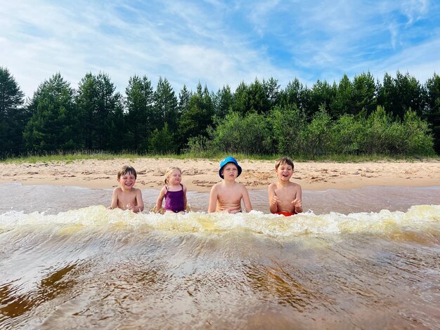 Niños divirtiéndose atrapando olas en el lago Ladoga Vacaciones de verano en la playa