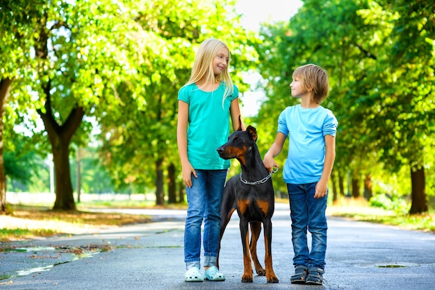 Niños con dobermann en el parque de verano.