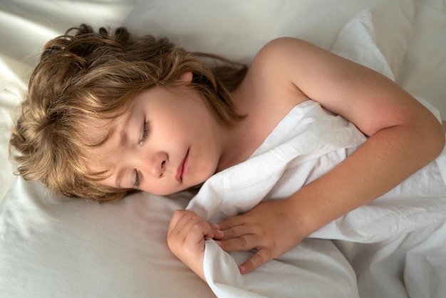 Los niños dormidos yace en la cama con los ojos cerrados