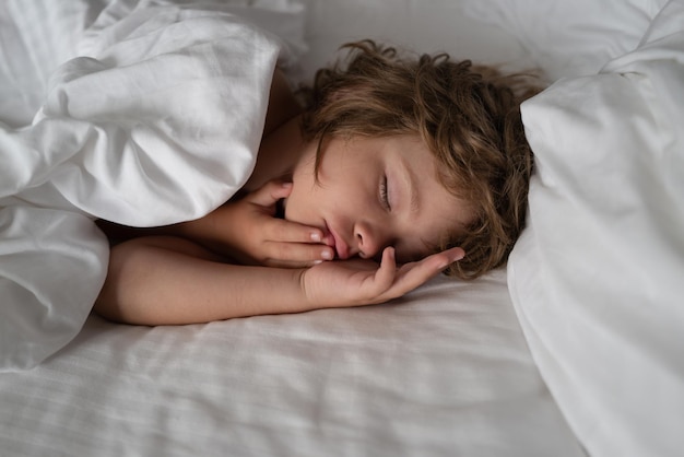 Los niños duermen en la cama. Buenas noches. Calma adorable niño acostado sobre suaves almohadas.