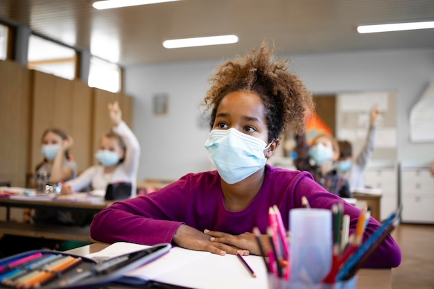 Niños en edad escolar con mascarilla en el aula durante la pandemia del virus corona.