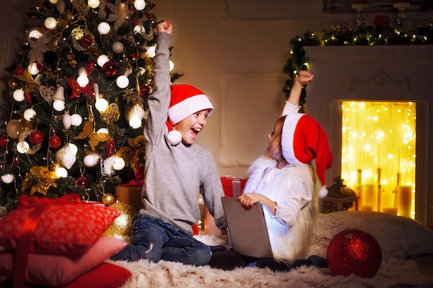 Niños emocionados cerca del árbol de navidad