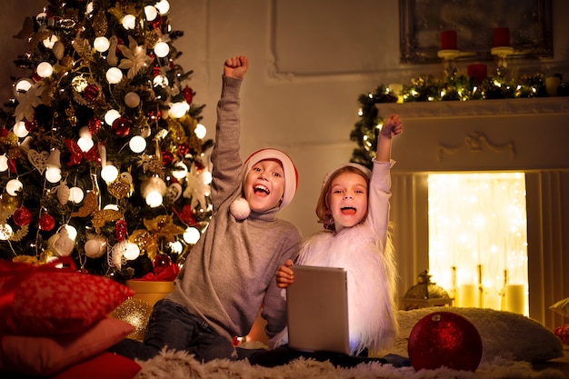 Niños emocionados cerca del árbol de navidad