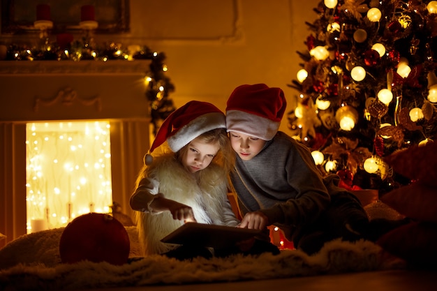 Niños emocionados cerca del árbol de navidad