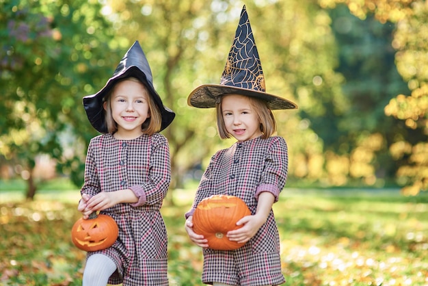 Niños encantadores en traje de bruja con calabazas de halloween