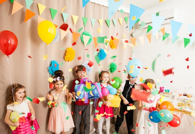 Foto niños encantadores vienen a la fiesta de cumpleaños de los amigos y dan regalos.