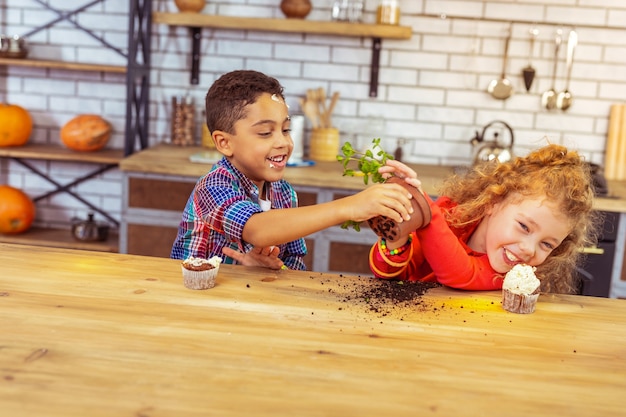 Para. Niños encantados que expresan positividad mientras juegan con la planta.