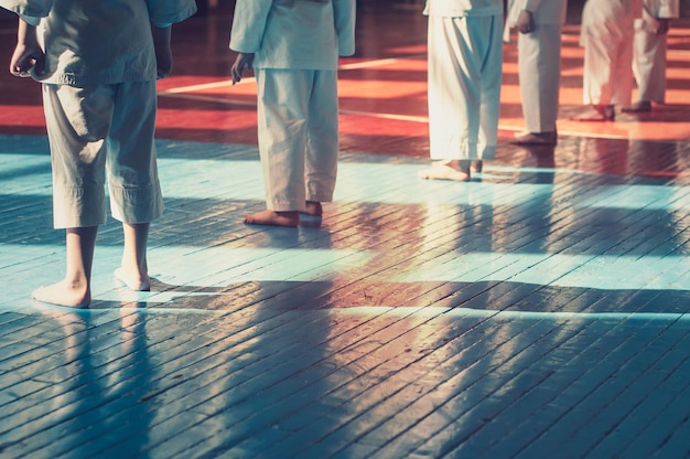 Niños entrenando en karatedo Atletas jóvenes en kimonos tradicionalmente blancos con cinturones de colores Banner con espacio para texto Estilo retro Para páginas web o impresión publicitaria Foto sin rostros