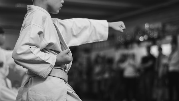 Niños entrenando en karatedo Entrenamiento de golpe de palma Entrenamiento deportivo y un estilo de vida saludable Foto de fondo en blanco y negro sin rostros