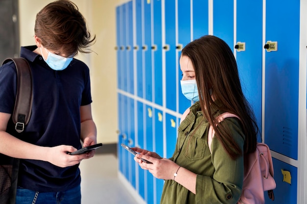 Niños escolares usando teléfonos inteligentes durante una pandemia