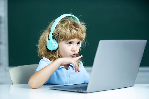 Niños de la escuela con computadora portátil y auriculares en clase en la escuela.