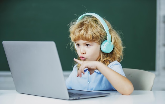 Niños de la escuela con computadora portátil y auriculares en clase en la escuela