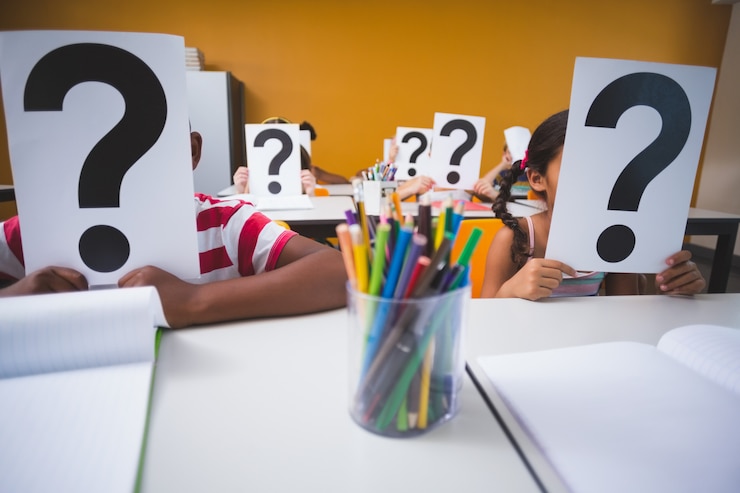 Foto niños de la escuela cubriendo su rostro con signo de interrogación