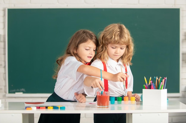 Niños de la escuela dibujando imágenes coloridas con lápices de colores en el aula