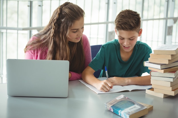 Niños de la escuela haciendo la tarea en la biblioteca