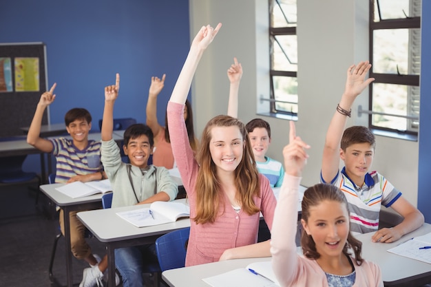 Niños de la escuela levantando la mano en el aula en la escuela