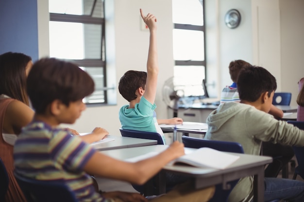 Foto niños de la escuela levantando la mano en el aula