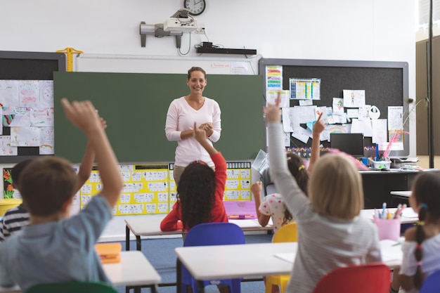 Niños de la escuela levantando la mano mientras están sentados en su silla