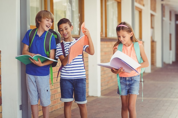 Niños de la escuela leyendo libros mientras camina en el pasillo