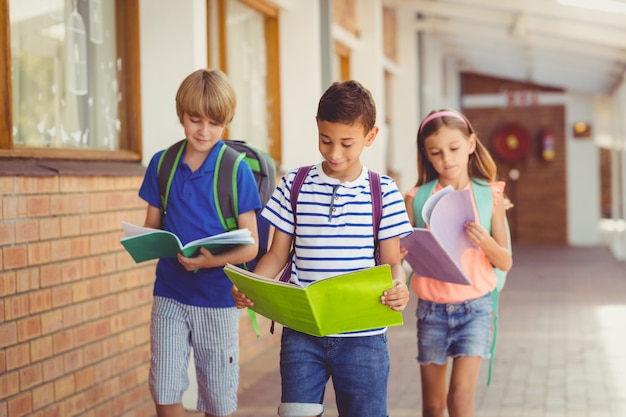 Niños de la escuela leyendo libros mientras camina en el pasillo