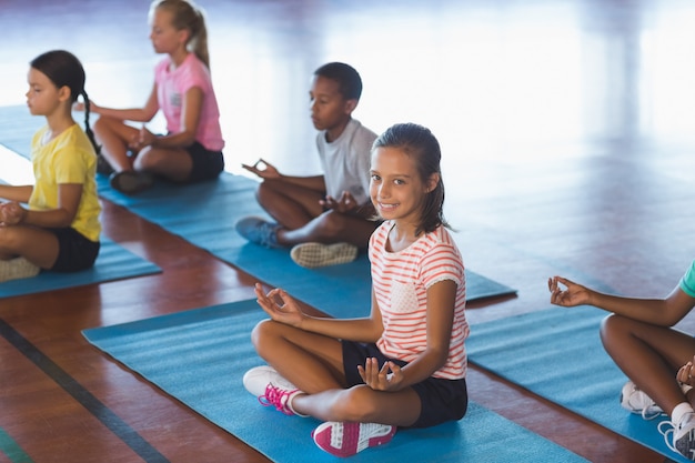 Niños de la escuela meditando durante la clase de yoga