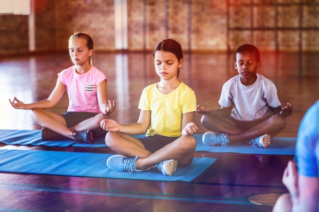 Foto niños de la escuela meditando durante la clase de yoga