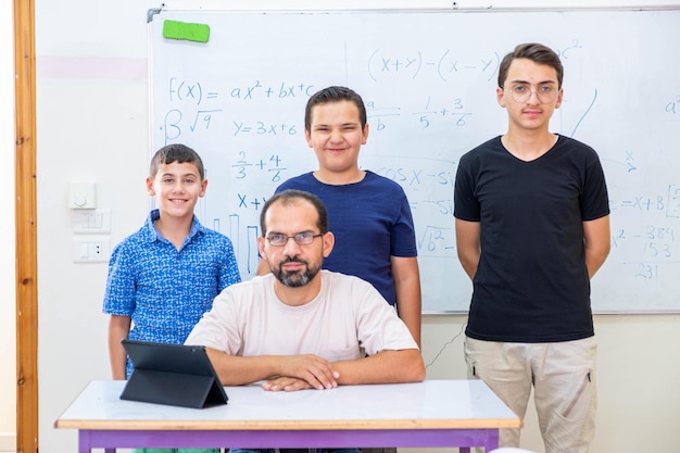 Niños de la escuela parados uno al lado del otro con el maestro mientras sonríen