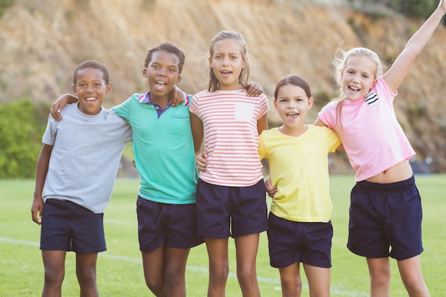 Niños de la escuela de pie con los brazos alrededor