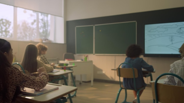 Niños de escuela sentados en escritorios en el aula durante la lección en la escuela primaria