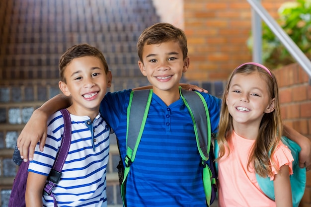 Foto niños de la escuela sonrientes de pie con el brazo alrededor