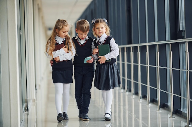 Niños de la escuela en uniforme junto con el teléfono en el corredor Concepción de la educación