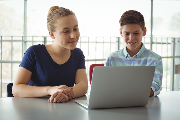 Niños de la escuela usando una computadora portátil en la biblioteca