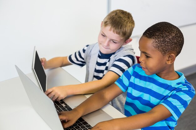 Foto niños de la escuela usando una computadora portátil y tableta digital en el aula